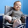 Jasper is registered to the contest to win money with this photo: baby, child, infant, smiling, happy, portrait, sitting, chair, high_chair, harness, gray_clothing, blue_background, indoor, face, eyes, hair, furniture, photography, cute, playful