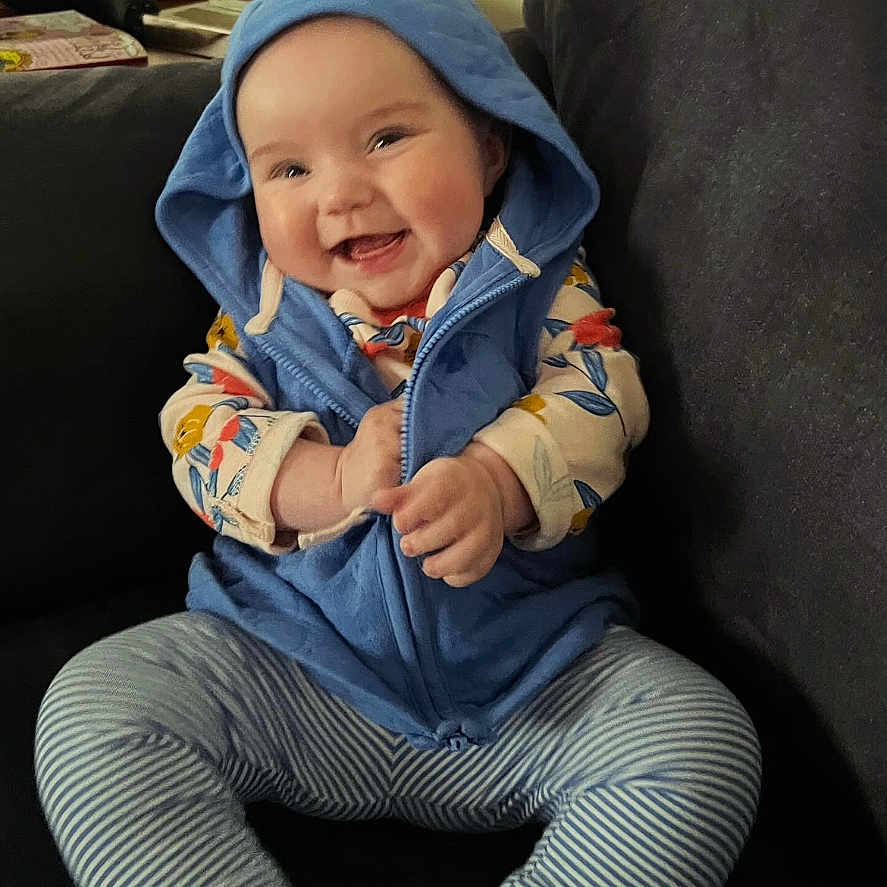 Madison joined the competition — help win amazing prizes! baby, clothing, coat, face, happy, hat, head, hood, hoodie, jacket, jeans, knitwear, pants, person, photography, portrait, sitting, smile, sweater, sweatshirt