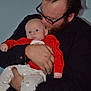 baby, man, holding, glasses, beard, red_clothing, white_pants, infant, portrait, indoor, affection, parent, child, closeup, human, love, cute, casual, expression, warmth