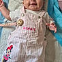 baby, smiling, infant, overalls, minnie_mouse, pink, white, striped, lying_down, quilted_mat, cute, happy, child, clothing, indoor, person, feet, face, head, young