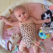 Ava a rejoint le concours — aidez-le/la à gagner de superbes lots ! baby, infant, playpen, toy, soft_toy, onesie, leopard_print, smile, child, cute, indoor, floor_mat, baby_gym, colorful, playtime, happy, person, skin, head, legs