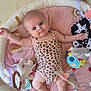baby, infant, playpen, toy, soft_toy, onesie, leopard_print, smile, child, cute, indoor, floor_mat, baby_gym, colorful, playtime, happy, person, skin, head, legs