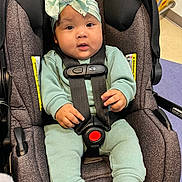 Aliyah is registered to the contest to win money with this photo: baby, child, car_seat, seatbelt, headwrap, bow, clothing, infant, cute, indoors, person, sitting, smile, socks, happy, face, young_child, secured, comfortable, portrait