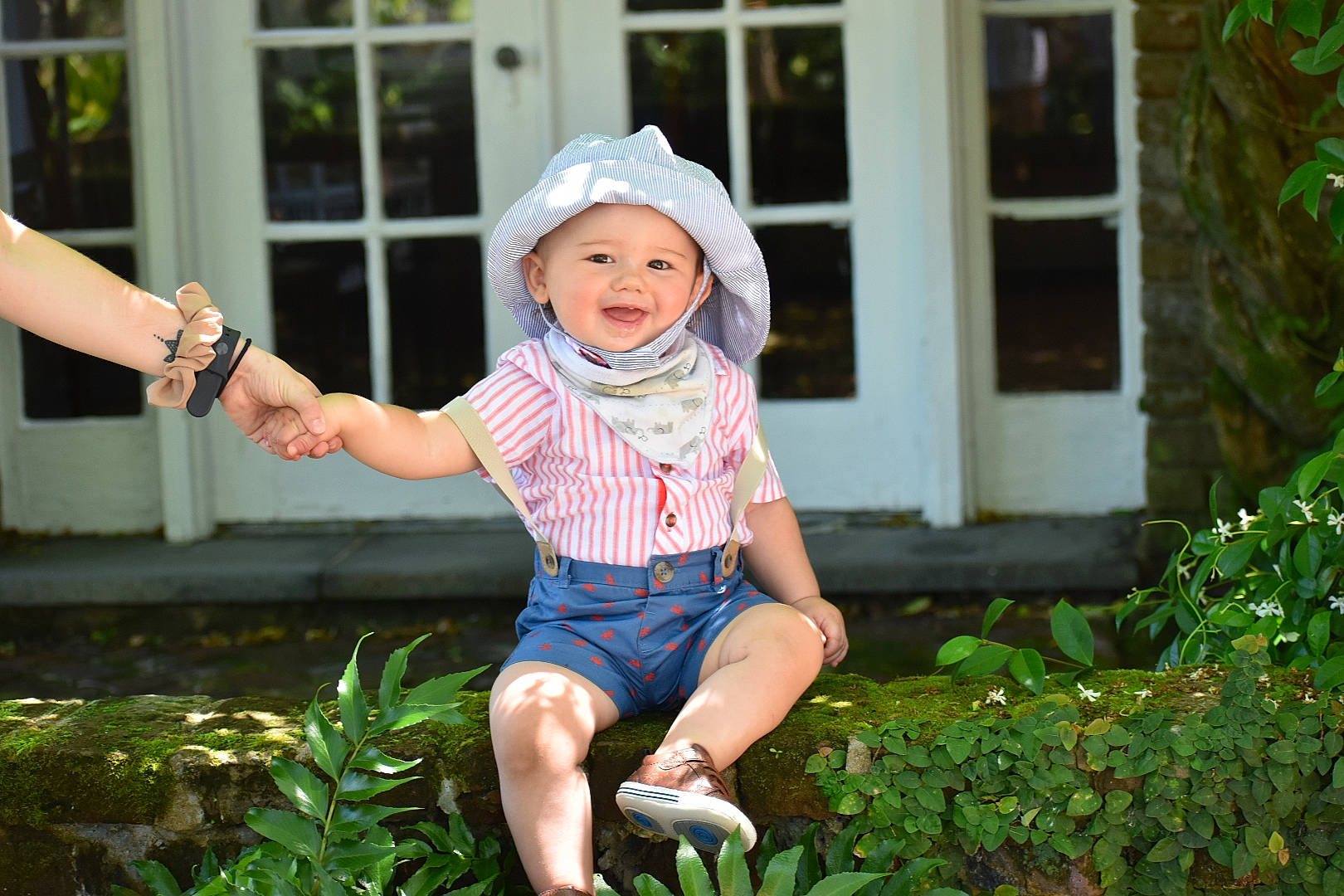 Braden is registered to the contest to win money with this photo: arm, baby, baby_toddler_clothing, barefoot, cap, foot, fun, grass, hand, happy, hat, headwear, human_leg, leisure, person, pink, plant, sitting, sleeve, summer