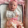 Lakelynn Rylie joined the competition — help win amazing prizes! baby, child, infant, portrait, face, smiling, indoors, pink, headband, bow, floral_clothing, dress, white_shirt, blanket, quilted_mat, lying_down, nursery, cute, seated, looking_at_camera