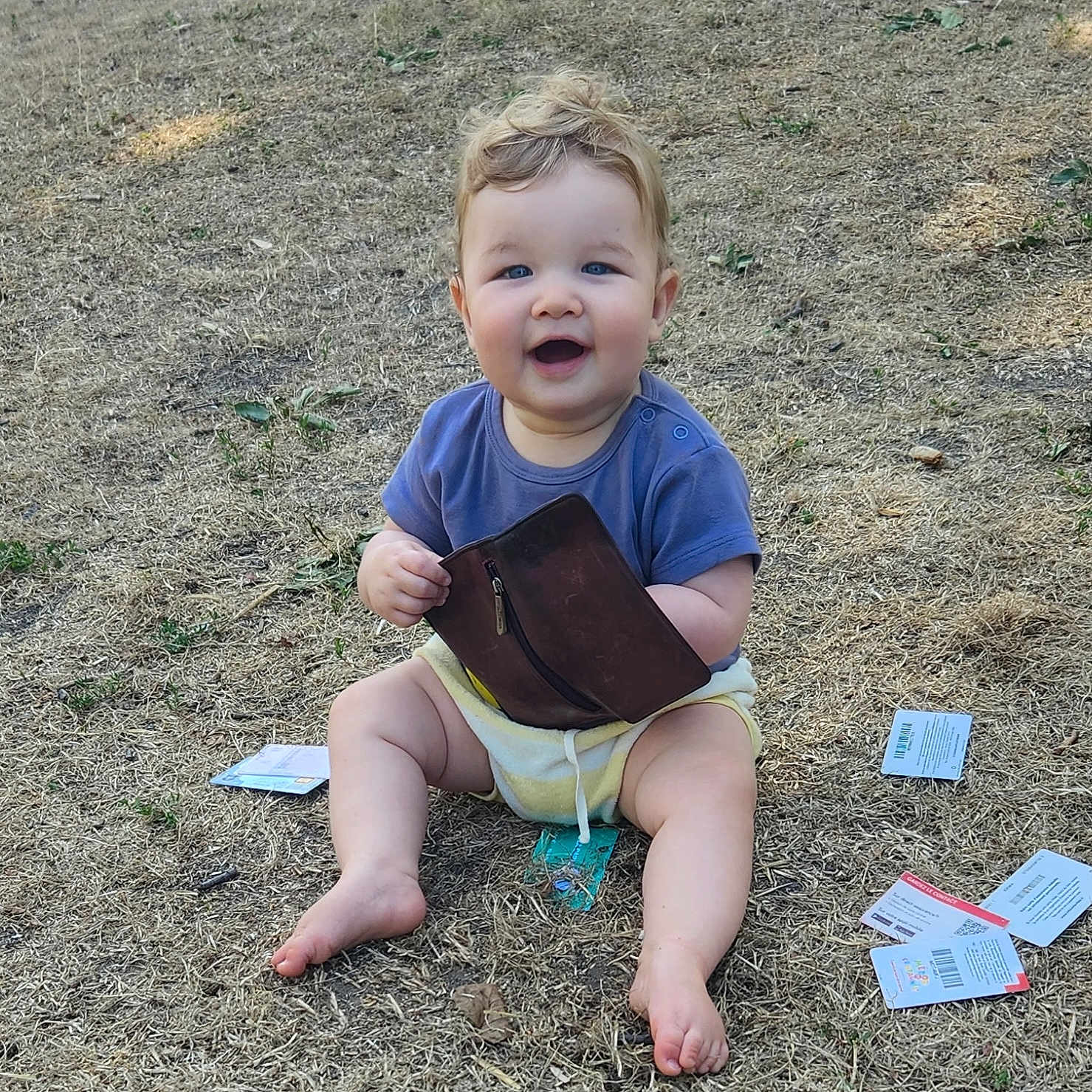 Leo a rejoint le concours — aidez-le/la à gagner de superbes lots ! baby, barefoot, cards, child, cute, daylight, face, grass, happy, nature, outdoor, person, playful, shorts, sitting, skin, smiling, tshirt, wallet, young