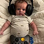 Stetson is registered to the contest to win money with this photo: baby, blanket, child, clothing, comfort, cute, expression, face, foot, gamer, gaming_controller, hand, headset, indoors, infant, lying_down, pacifier, playful, technology, toy
