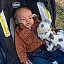 baby, car_seat, casual, child, clothing, cow_toy, cute, expression, face, grass, hand, infant, jeans, outdoor, person, plush_toy, seated, shirt, stroller, toy