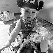 Grayson joined the competition — help win amazing prizes! child, toddler, cowboy_hat, bandana, plush_toy, rocking_horse, indoor, wooden_floor, black_and_white, baby, toy, play, smiling, cute, person, infant, hat, costume, fun, portrait