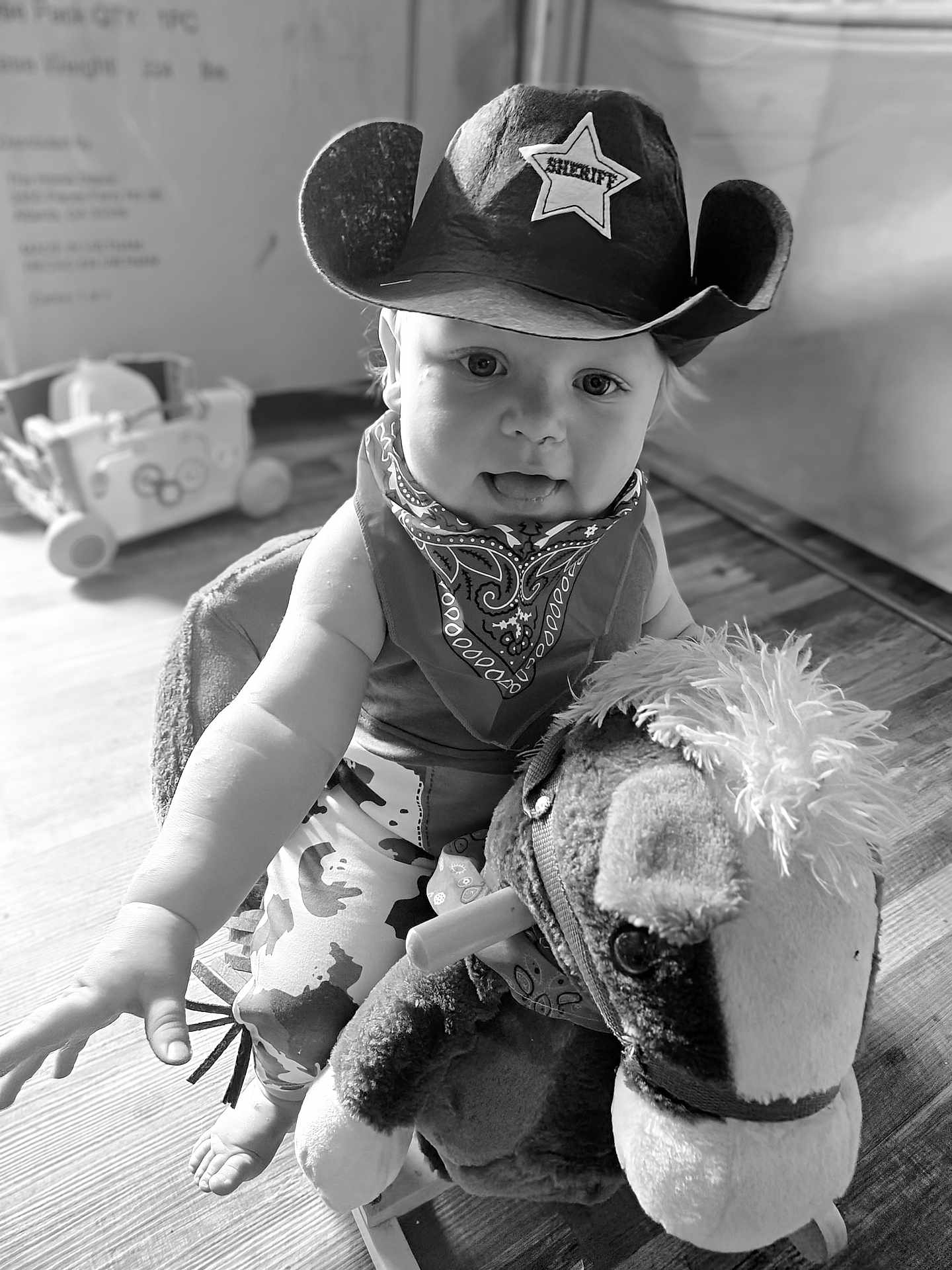 Grayson joined the competition — help win amazing prizes! child, toddler, cowboy_hat, bandana, plush_toy, rocking_horse, indoor, wooden_floor, black_and_white, baby, toy, play, smiling, cute, person, infant, hat, costume, fun, portrait