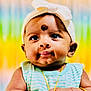 baby, child, headband, bow, striped_clothing, gold_jewelry, bracelet, necklace, face, eyes, skin, hand, curious, portrait, closeup, colorful_background, indoor, infant, cute, expression