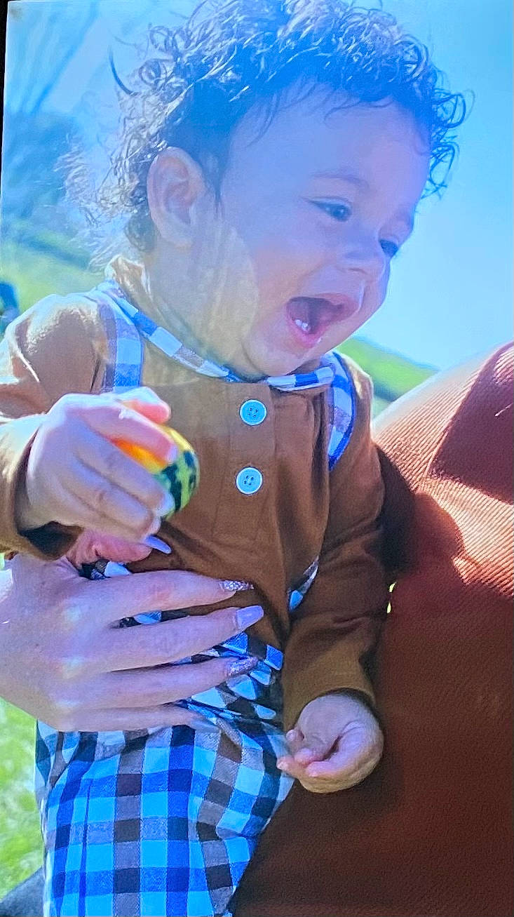 Tylan is registered to the contest to win money with this photo: arm, baby, baby_toddler_clothing, blue, facial_expression, finger, fun, gesture, grass, hand, happy, people_in_nature, person, photograph, pink, skin, smile, summer, tartan, thumb
