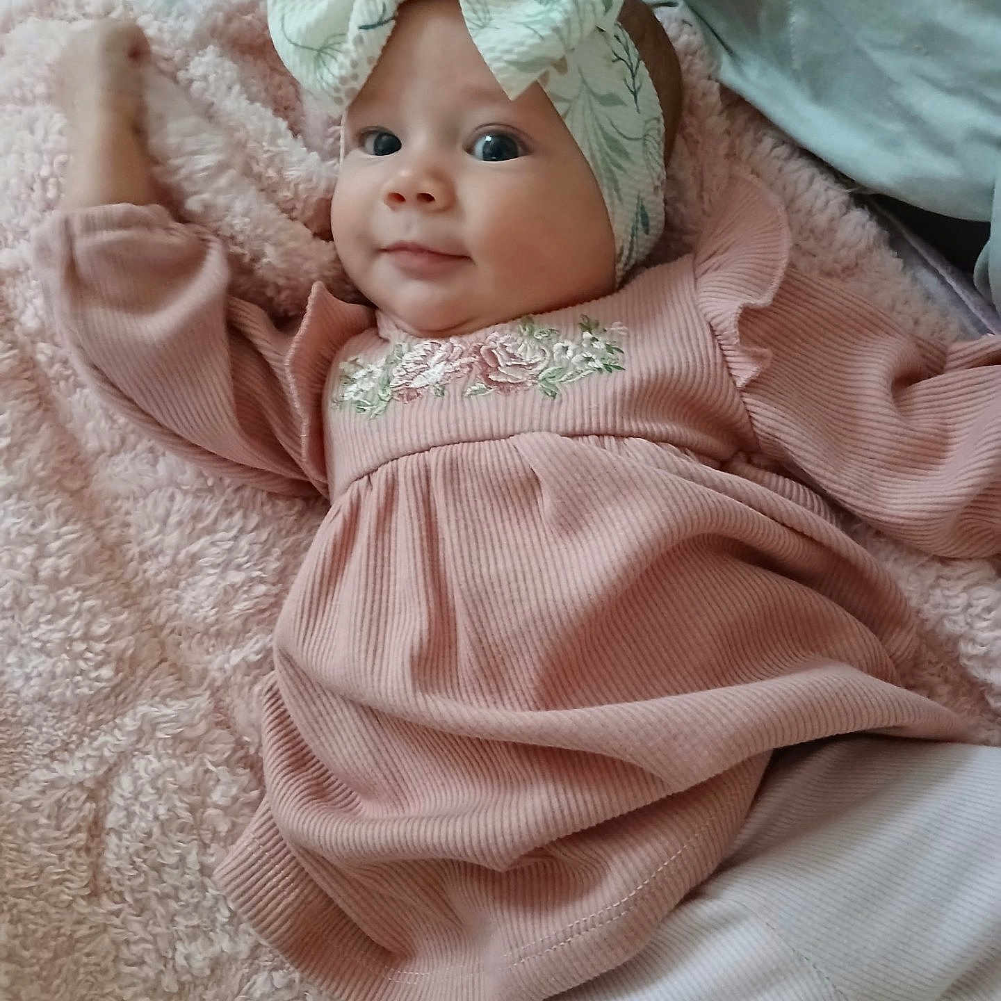 Alina is registered to the contest to win money with this photo: apparel, baby, blanket, child, closeup, cozy, cute, face, happy, headband, headwear, indoor, infant, lying_down, person, pink_dress, portrait, smile, soft_texture, young_child