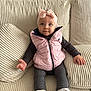 baby, blue_eyes, child, clothing, couch, cozy, cute, expression, footwear, hands, headband, indoor, infant, pillows, pink_bow, pink_vest, portrait, seated, textured_fabric, white_sneakers