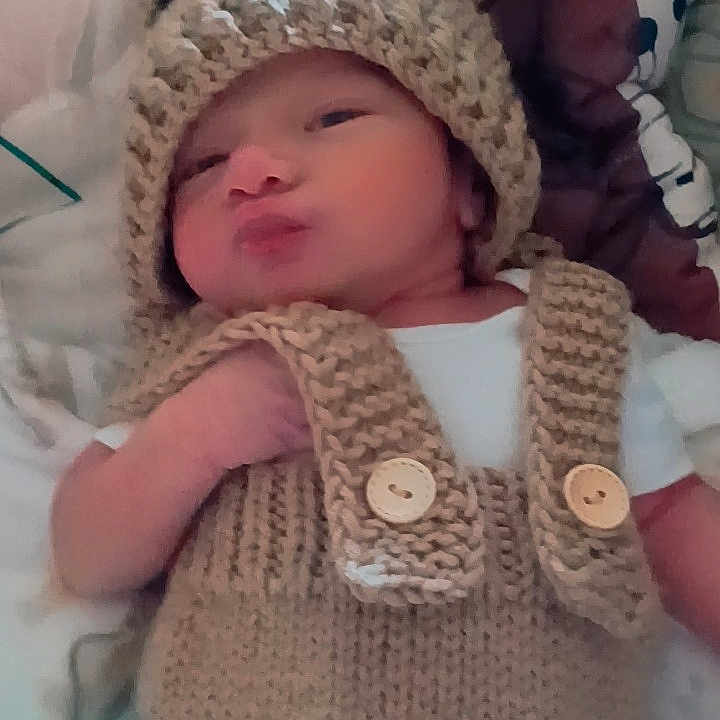 Mico is registered to the contest to win money with this photo: baby, bear_hat, blanket, button, child, cozy, cute, face, hand, headwear, indoors, infant, knitted_clothing, laying_down, newborn, pillow, portrait, sleeping_area, soft_texture, warm_colors