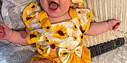 Alora-Mae joined the competition — help win amazing prizes! baby, child, smiling, sunflower, hat, yellow, clothing, bed, pillow, remote_control, happy, cute, infant, foot, cheerful, portrait, indoors, fabric, texture, playful
