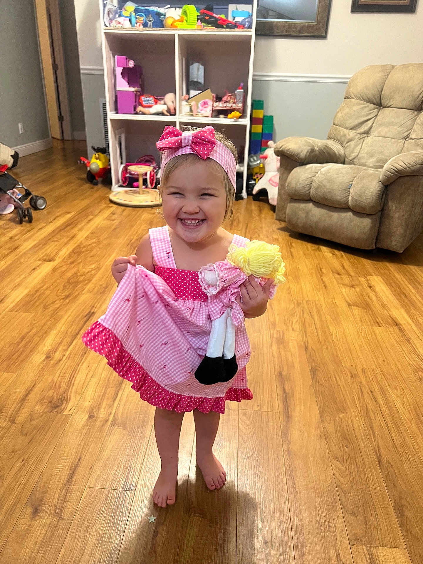 Drue joined the competition — help win amazing prizes! armchair, barefoot, child, cute, doll, furniture, girl, happy, headband, home, indoors, living_room, person, pink_dress, play, smiling, toddler, toys, wooden_floor, young_child