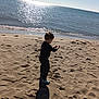 Timaé a rejoint le concours — aidez-le/la à gagner de superbes lots ! child, beach, sand, ocean, water, sunlight, shadow, footprints, sky, shore, casual_clothing, sneakers, outdoor, daylight, nature, playing, coast, vacation, seashore, toddler