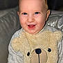 applique, baby, babylaughing, clothing, couch, cushion, face, furniture, happy, head, homedecor, knitwear, laughing, pattern, person, photography, portrait, sitting, smile, sweater