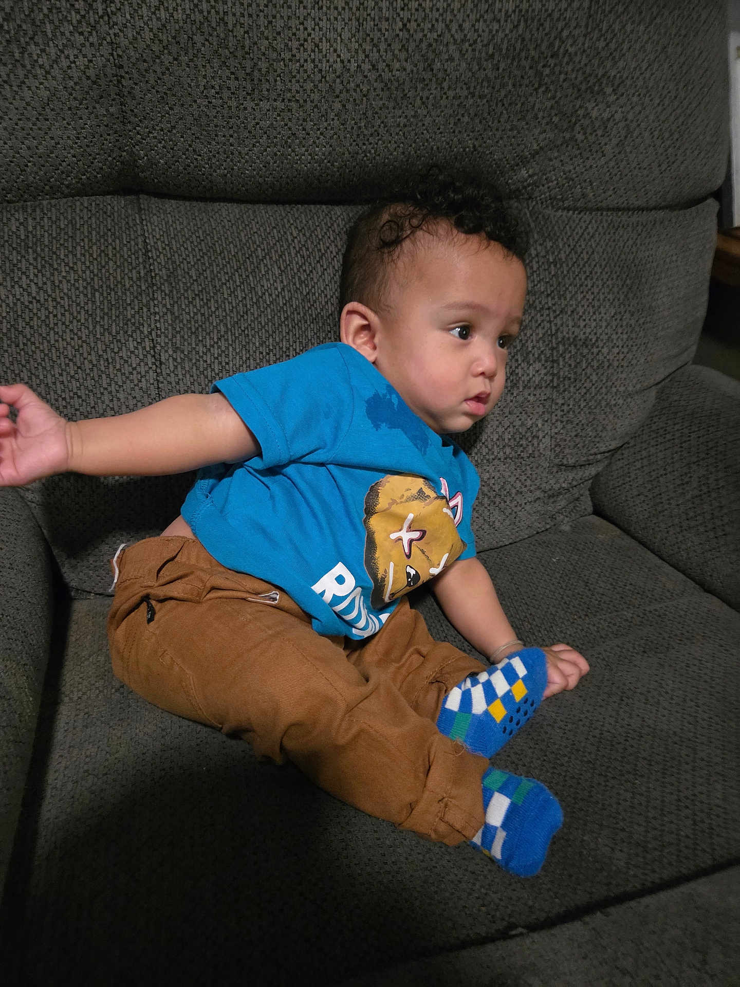Nalo joined the competition — help win amazing prizes! child, baby, toddler, curly_hair, blue_shirt, brown_pants, checked_socks, socks, sofa, couch, seat, living_room, infant, portrait, sitting, stain, expression, arm, hand, furniture