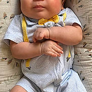Caden is registered to the contest to win money with this photo: baby, infant, child, cute, smiling, lying_down, cushion, floral_pattern, clothing, yellow_socks, cartoon_characters, bow_tie, suspenders, indoors, portrait, skin, face, hands, feet, happy