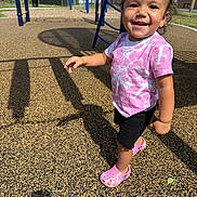 Ella joined the competition — help win amazing prizes! toddler, child, smiling, playground, outdoor, sunny, pink_shoes, tie_dye_shirt, black_shorts, shadow, happy, person, recreation, daylight, play_equipment, fence, trees, grass, urban, park