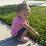 Ella is registered to the contest to win money with this photo: toddler, child, pink_shirt, denim_shorts, crocs, sidewalk, grass, clover, flower, sunlight, shadow, outdoor, curious, crouching, earrings, hair_tie, nature, summer, daytime, casual_clothing