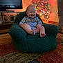 Waylon joined the competition — help win amazing prizes! baby, child, smiling, chair, plush, christmas_tree, holiday_lights, indoor, carpet, television, furniture, person, living_room, happy, cozy, decor, footwear, couch, wood_floor, home