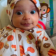 Wania is registered to the contest to win money with this photo: baby, infant, headband, onesie, pumpkin, donut, patterned_clothing, monkey, palm_tree, colorful, wide_eyes, cute, portrait, child, indoor, smiling, seated, playful, background, close_up
