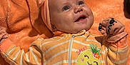 Brynleigh is registered to the contest to win money with this photo: baby, child, headband, mittens, blanket, orange, smile, face, person, infant, cute, striped_clothing, zipped_onesie, soft_texture, happy, lying_down, closeup, cozy, interaction, sibling