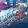 toddler, child, gift_bag, plaid, indoor, carpet, adult_hand, chair, socks, person, smile, hair, floor, jeans, sitting, cozy, home, furniture, happy, curious