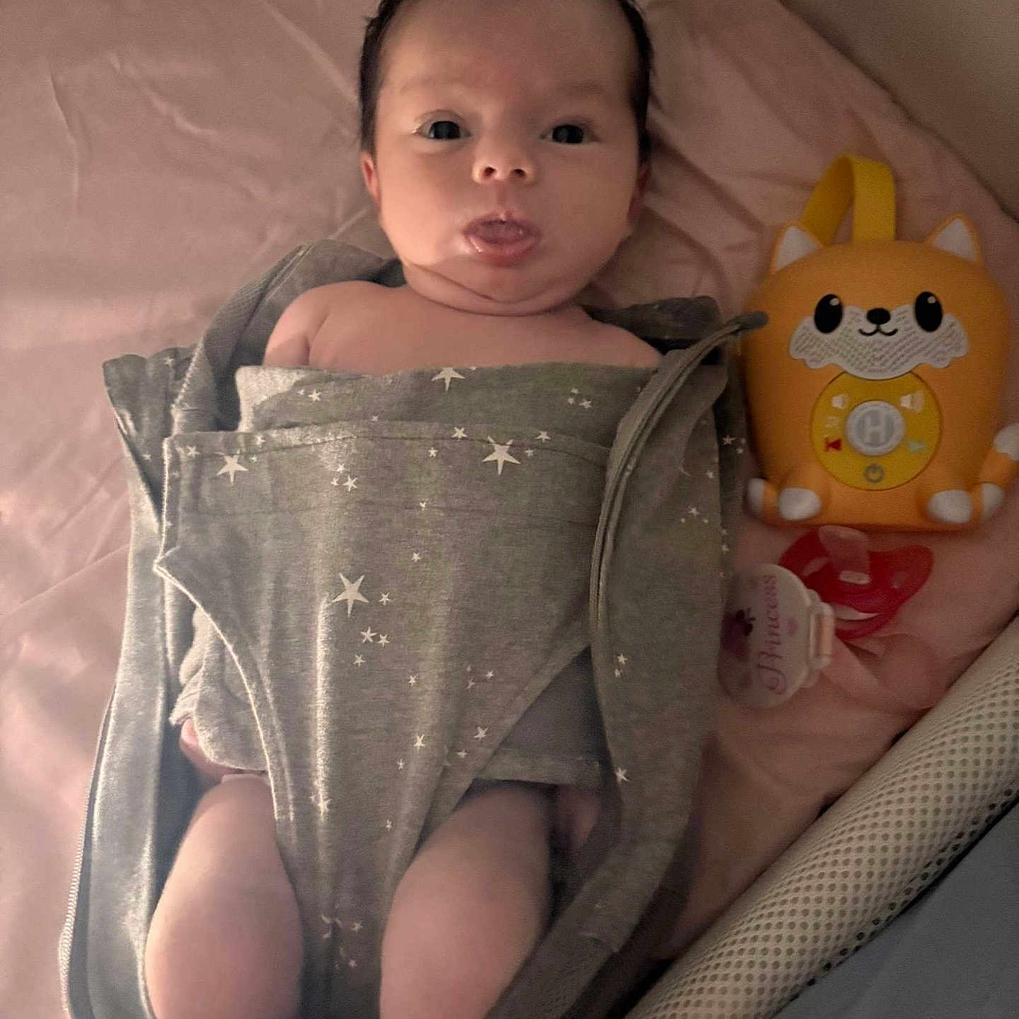 Elleigh is registered to the contest to win money with this photo: baby, bed, blanket, child, cute, face, fox, gray, indoor, infant, lying_down, newborn, pacifier, person, pink, sleeping_area, soft_lighting, swaddle, tongue, toy