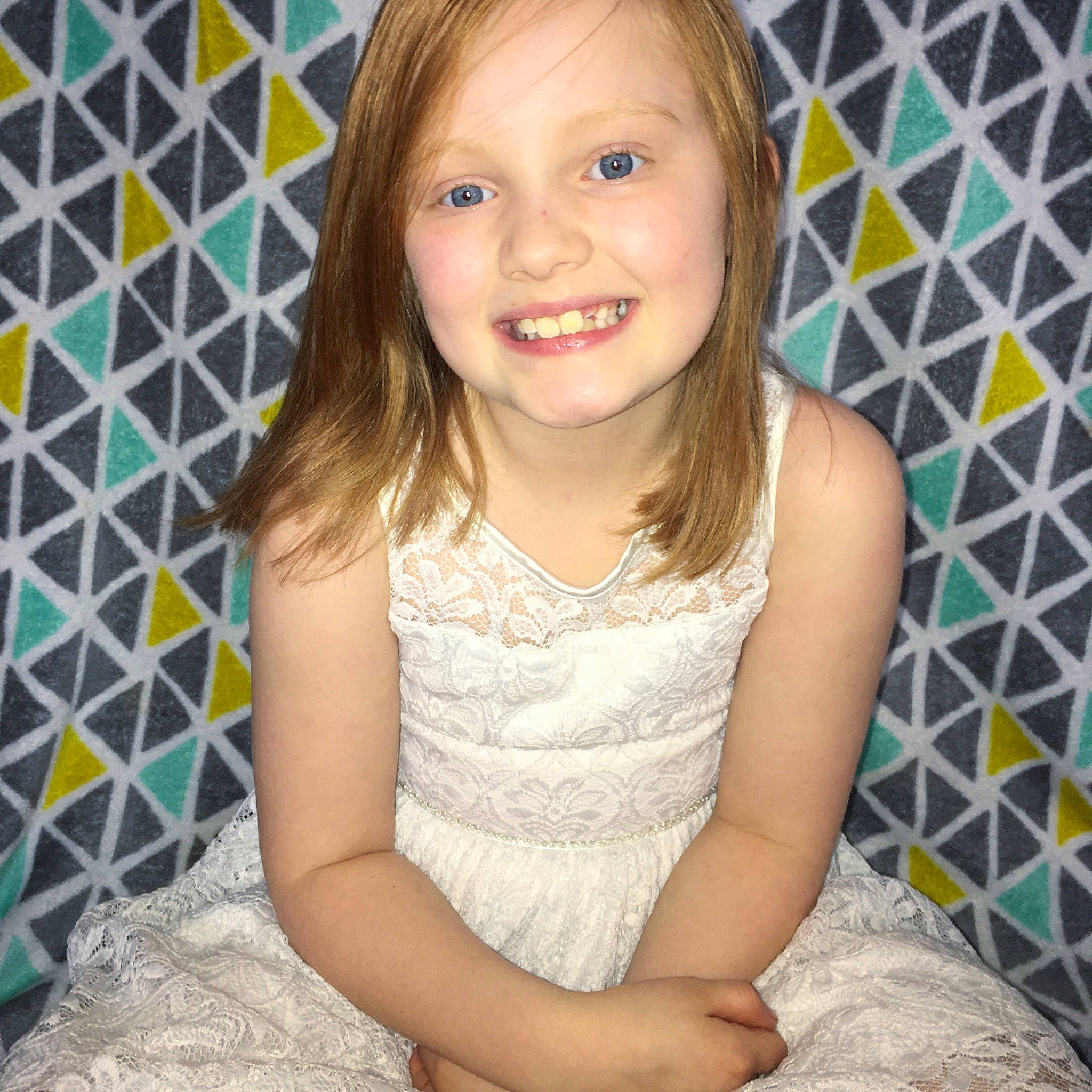 Emma is registered to the contest to win money with this photo: baby_toddler_clothing, bangs, blond, brown_hair, child_model, clothing, day_dress, dress, embellishment, feathered_hair, iris, joy, mouth, one_piece_garment, pattern, person, sitting, skin, textile, tooth