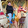 amusement_park, camel, carousel, child, clothing, colorful, decorative, entertainment, fun, happy, jacket, joy, outdoor, person, playful, ride, seat, smile, sneakers, vintage