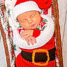 baby, infant, sleeping, knitted_clothing, santa_hat, red_clothing, white_clothing, basket, blanket, holiday_theme, christmas, festive, pattern, fabric, plush, cute, peaceful, child, portrait, wrapped