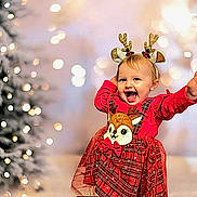 Milana a rejoint le concours — aidez-le/la à gagner de superbes lots ! toddler, child, smiling, holiday, christmas_tree, reindeer_antlers, festive_clothing, red_dress, sparkles, happy, celebration, indoors, cute, holiday_decor, bokeh, portrait, joyful, winter, festive, holiday_season