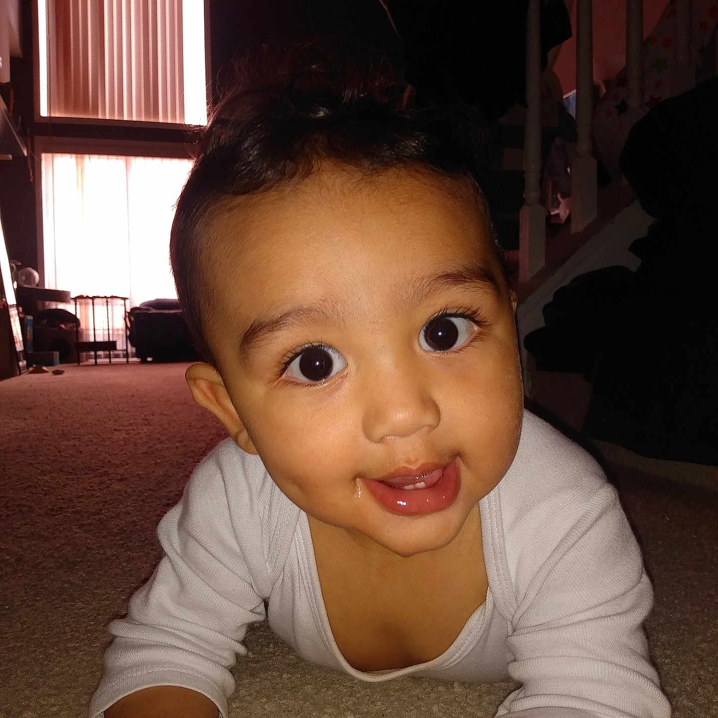 Noah joined the competition — help win amazing prizes! baby, candid, carpet, cheeky_smile, child, curious, cute, eyes, face, floor, home, indoor, living_room, natural_light, person, portrait, smiling, stairs, white_clothing, window