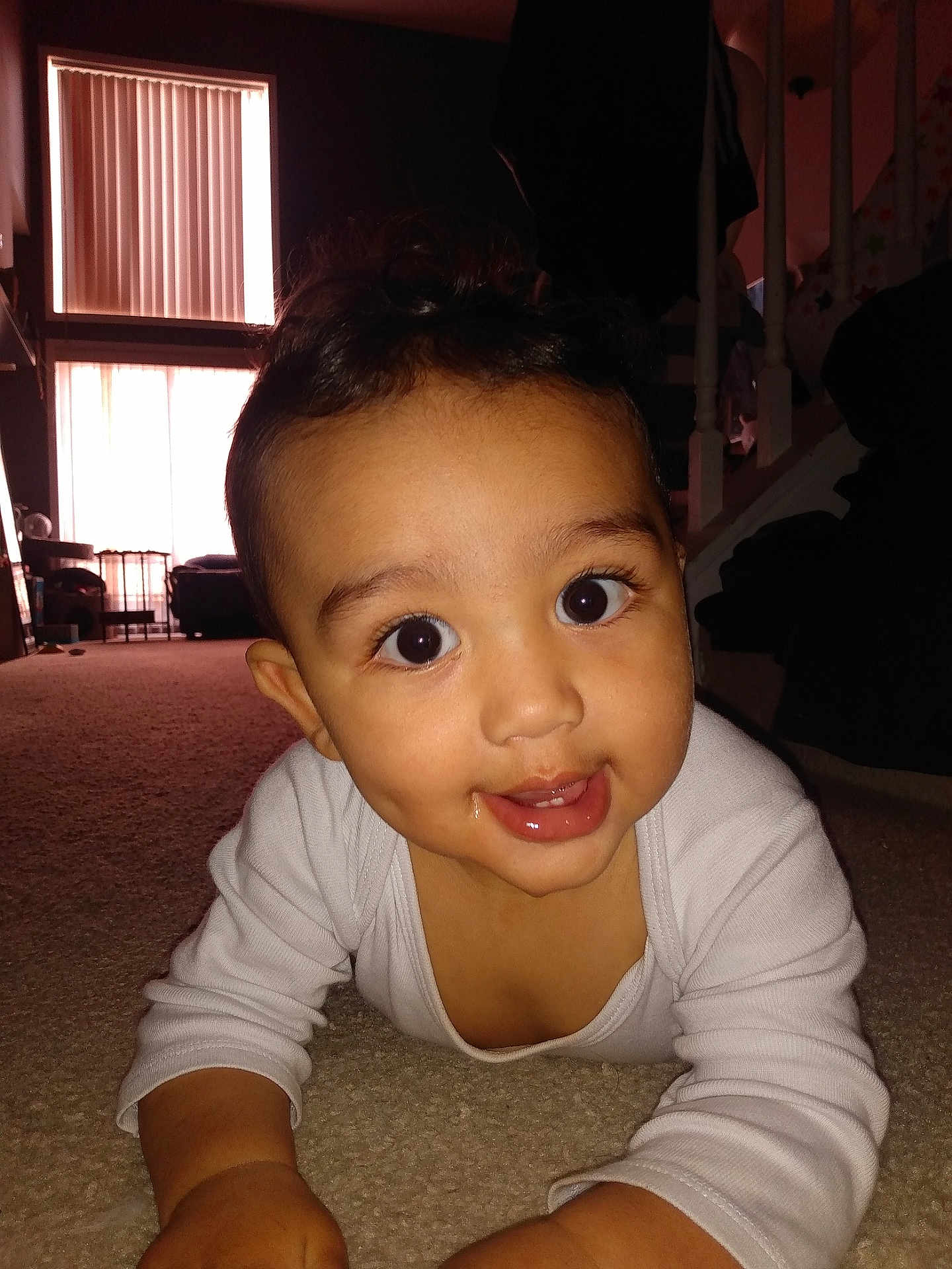 Noah joined the competition — help win amazing prizes! baby, child, indoor, carpet, curious, smiling, face, eyes, white_clothing, living_room, window, stairs, natural_light, candid, person, floor, home, cheeky_smile, cute, portrait