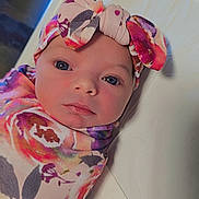 Amelya joined the competition — help win amazing prizes! baby, infant, swaddle, headband, bow, floral_pattern, closeup, face, portrait, newborn, soft, cute, child, lying_down, bright_eyes, colorful, fabric, peaceful, skin, indoors