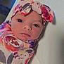 baby, infant, swaddle, headband, bow, floral_pattern, closeup, face, portrait, newborn, soft, cute, child, lying_down, bright_eyes, colorful, fabric, peaceful, skin, indoors
