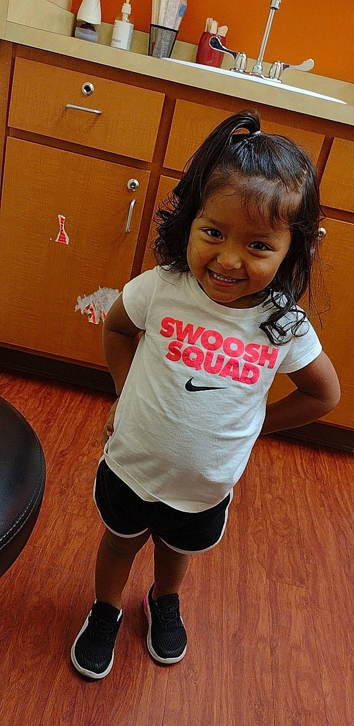 Isabella is registered to the contest to win money with this photo: arm, baby_toddler_clothing, flooring, fun, hair, happy, human, joint, joy, knee, leg, neck, person, shorts, skin, sleeve, smile, standing, t_shirt, thigh