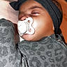 Kailani joined the competition — help win amazing prizes! baby, infant, sleeping, pacifier, headband, bow, portrait, close_up, face, child, indoors, gray_clothing, patterned_clothing, cozy, resting, peaceful, soft_lighting, brown_skin, baby_fashion, candid