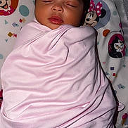 Kailani is registered to the contest to win money with this photo: baby, newborn, sleeping, swaddled, pink_blanket, crib, infant, portrait, face, closed_eyes, peaceful, indoors, bedding, cartoon_blanket, minnie_mouse, colorful, nursery, lying_down, cute, child