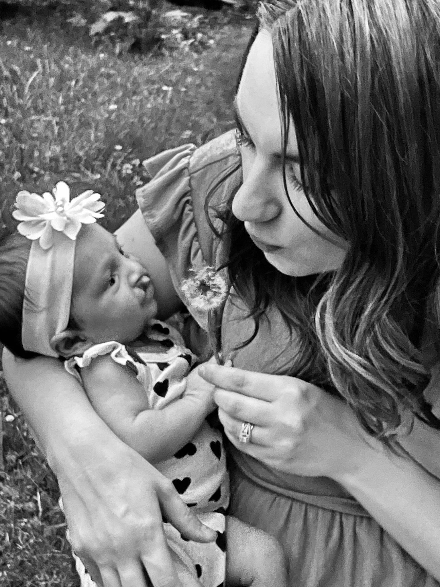 Myla Rose is registered to the contest to win money with this photo: arm, baby, black, black_and_white, face, finger, flower, gesture, grass, hair, hairstyle, hand, happy, interaction, people_in_nature, person, photograph, plant, smile, style