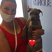 Tyson a rejoint le concours — aidez-le/la à gagner de superbes lots ! woman, face_mask, red_dress, puppy, dog, holding, indoor, door, light, wall, sign, rings, watch, white_purse, heart_emoji, floor, short_hair, casual, portrait, smile