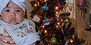 Lyrik joined the competition — help win amazing prizes! baby, bib, bow, child, christmas_tree, clothing, cute, decorations, face, festive, frame, hand, holiday, indoor, lights, ornaments, person, photograph, smile, wall