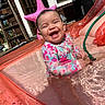 baby, child, infant, pool, water, swimsuit, inflatable_pool, smile, happy, outdoor, sunlight, starfish_float, hose, splash, play, summer, fun, joy, cute, sitting