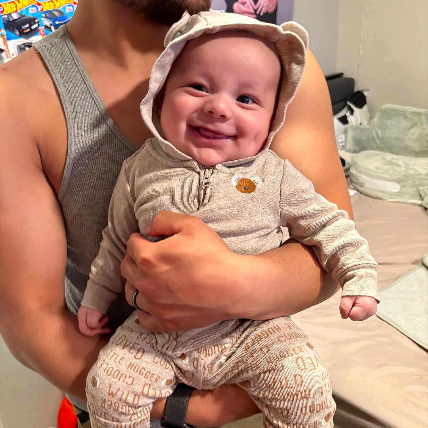 Matias is registered to the contest to win money with this photo: adult, baby, bedroom, clothing, cute, face, family, hand, happy, holding, indoors, infant, love, pajamas, parent, person, portrait, smiling, tank_top, toy