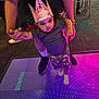 child, baby, party_hat, led_floor, colorful_lights, indoor, adult_hands, holding_hands, camouflage_shorts, socks, sneakers, carpet, party, celebration, portrait, curious_expression, floor_tiles, neon_lighting, cute, person
