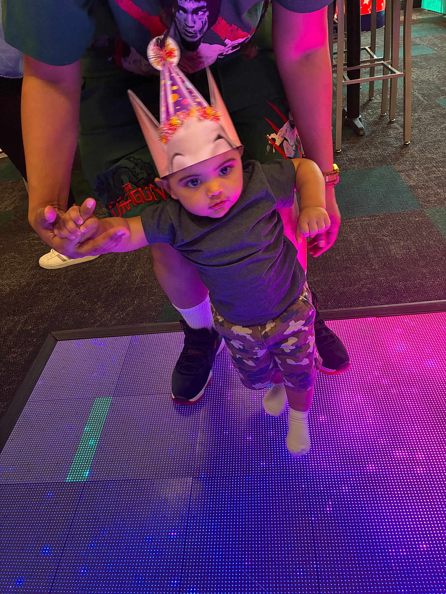 Major joined the competition — help win amazing prizes! child, baby, party_hat, led_floor, colorful_lights, indoor, adult_hands, holding_hands, camouflage_shorts, socks, sneakers, carpet, party, celebration, portrait, curious_expression, floor_tiles, neon_lighting, cute, person